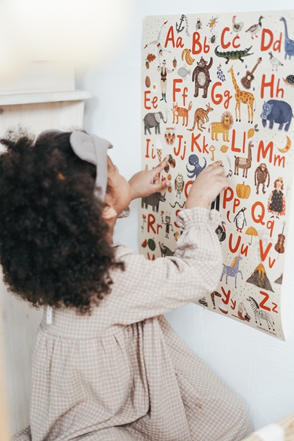 Schülerin vor Plakat mit Tieren und Buchstaben